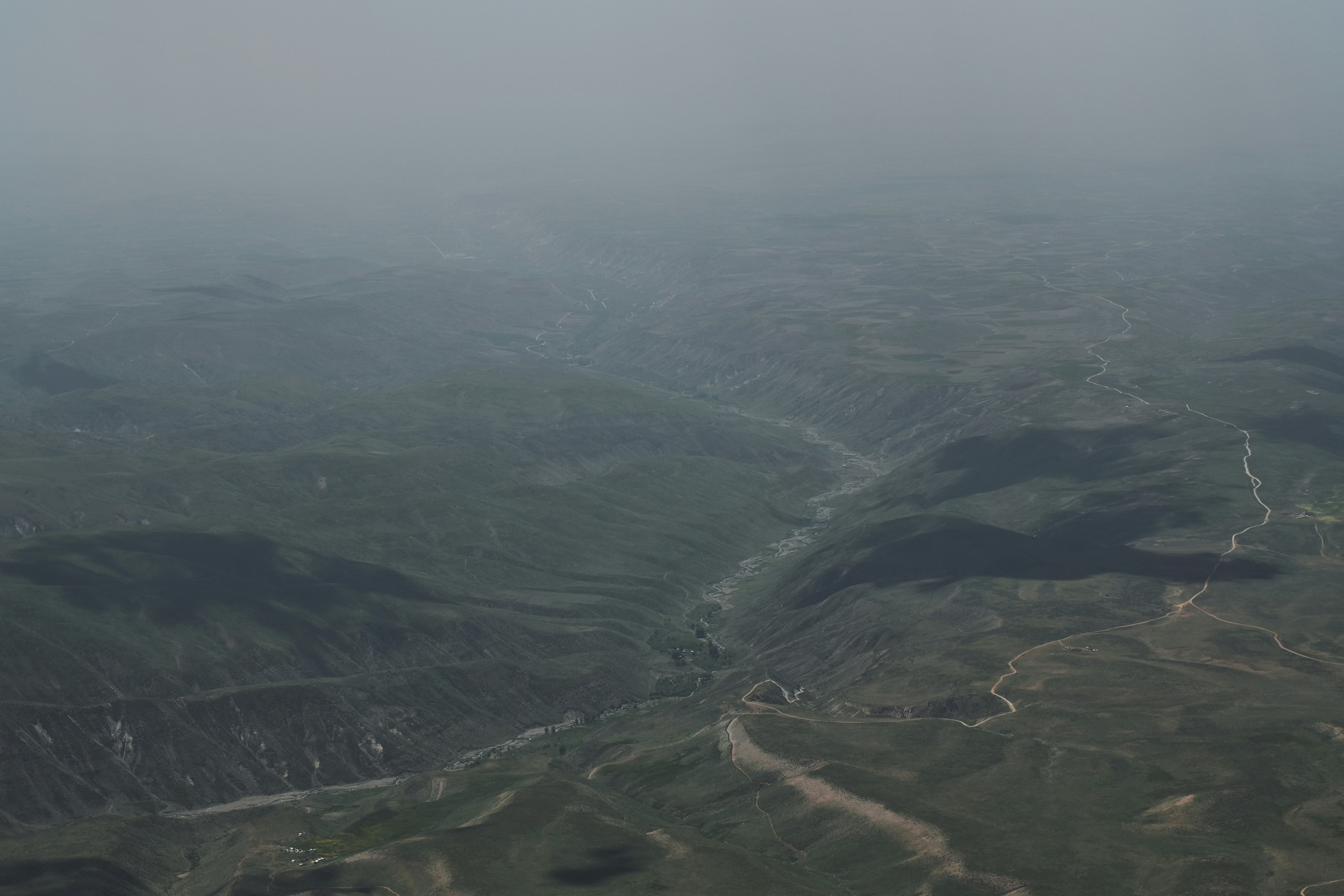 Aerial view of green valley with winding river, bright daylight, open landscape