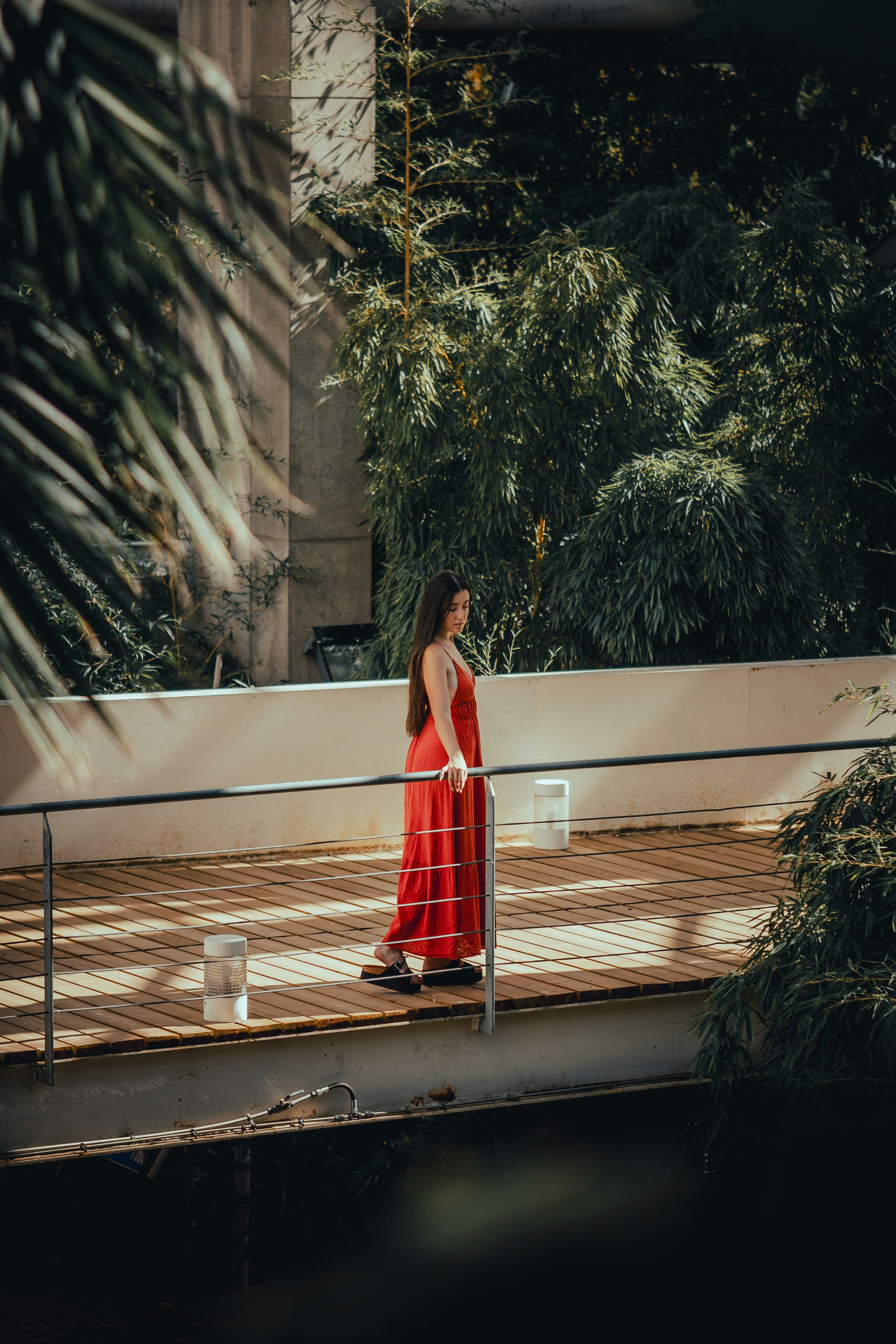 a woman in a red dress walking across a bridge