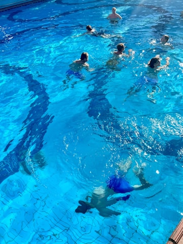 A group of swimmers training in an outdoor pool under a bright sunny sky