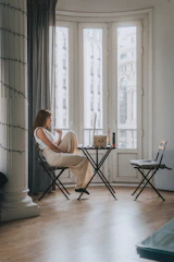 A calm, inviting student sitting comfortably with a laptop, engaging in an online consultation in a softly lit dorm room.