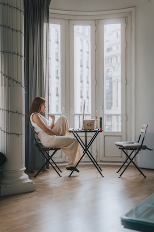 A relaxed student sitting by a window using the planner on a laptop, warm natural light softly highlighting the sage and beige theme.