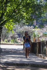 A person happily checking job alerts on their smartphone in a sunny park.