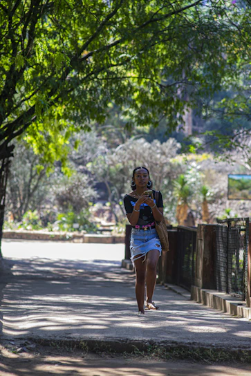 A smiling person using the Vitalia app on their phone while enjoying a morning walk in the park.