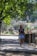 A person walking in a park, enjoying the outdoors while checking their mobile phone.