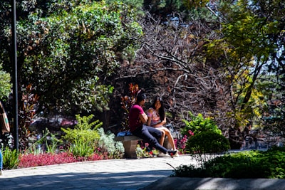 A couple sharing a quiet moment sitting on a blanket near blooming flowers in a sunny park.
