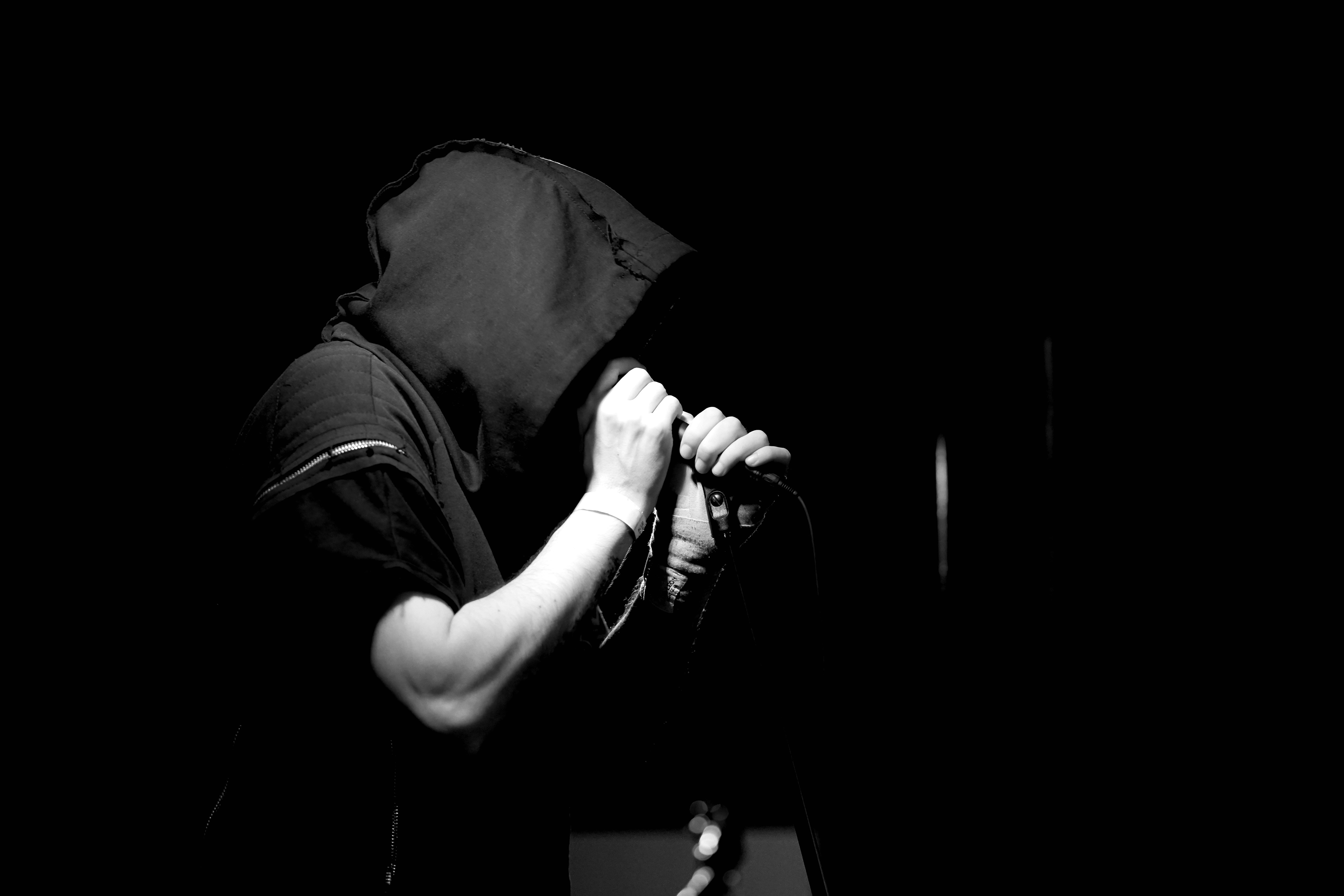 Performer with hood holding microphone during live show