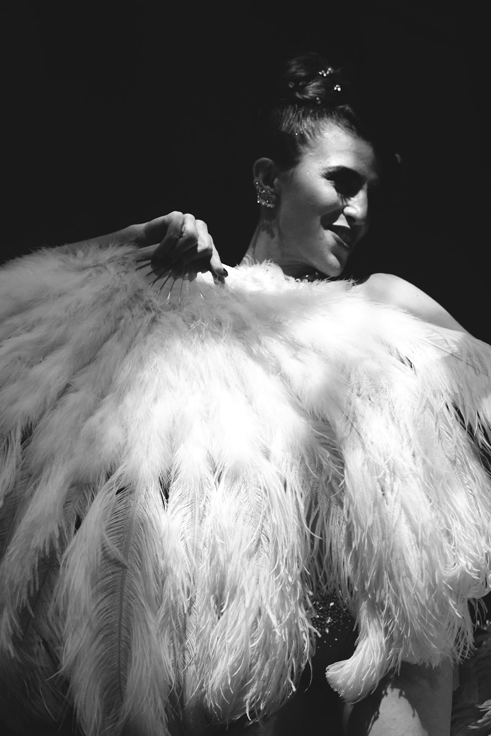 a black and white photo of a woman in a feather coat