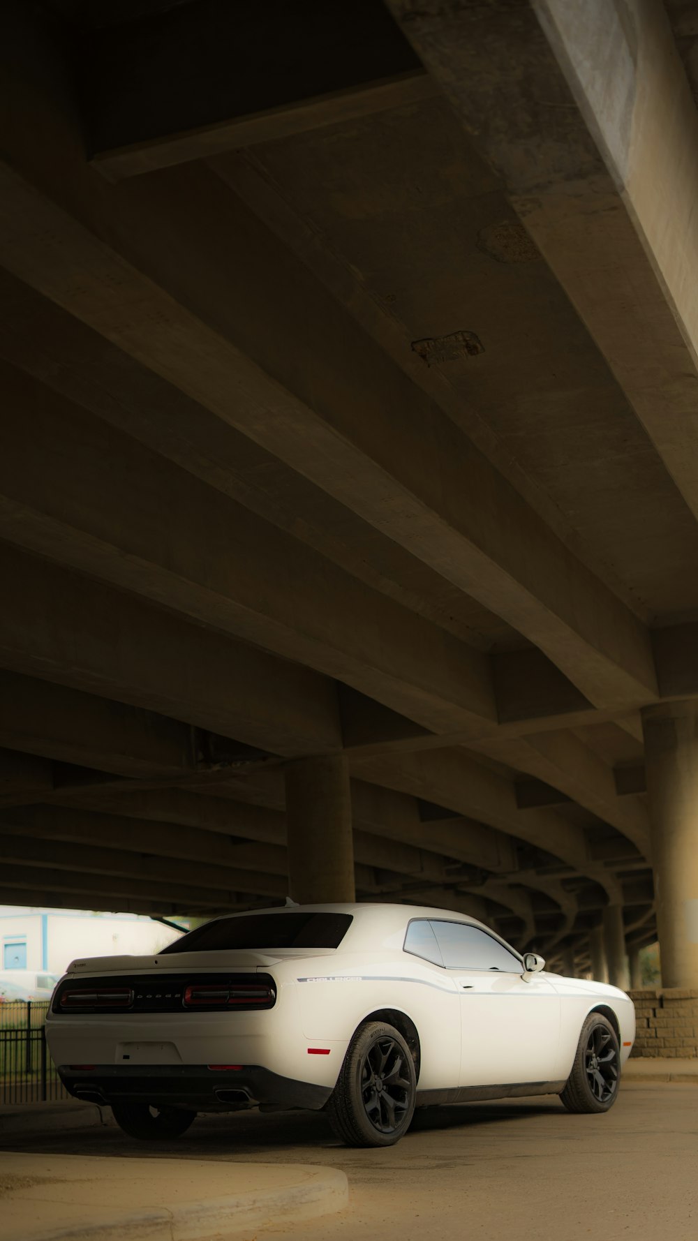 a white car is parked under a bridge