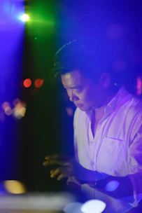 A vibrant behind-the-scenes shot of a music video shoot with colorful lighting and a focused director.