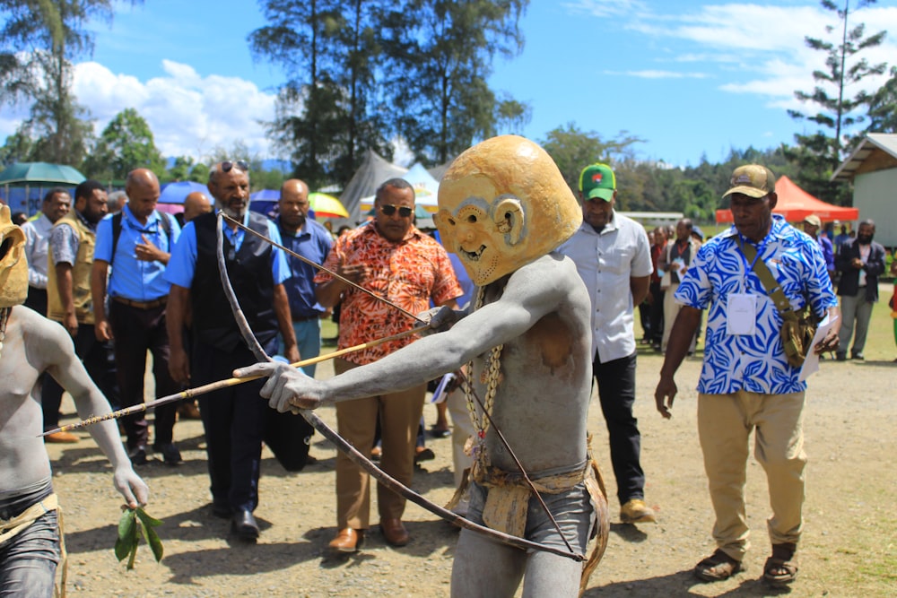 a group of people standing around a man with a bow and arrow