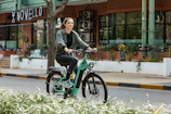 A happy tourist riding an e-bike along a tree-lined path inside Central Park with skyscrapers in the background