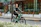 Man riding an electric bike on a city street with modern buildings