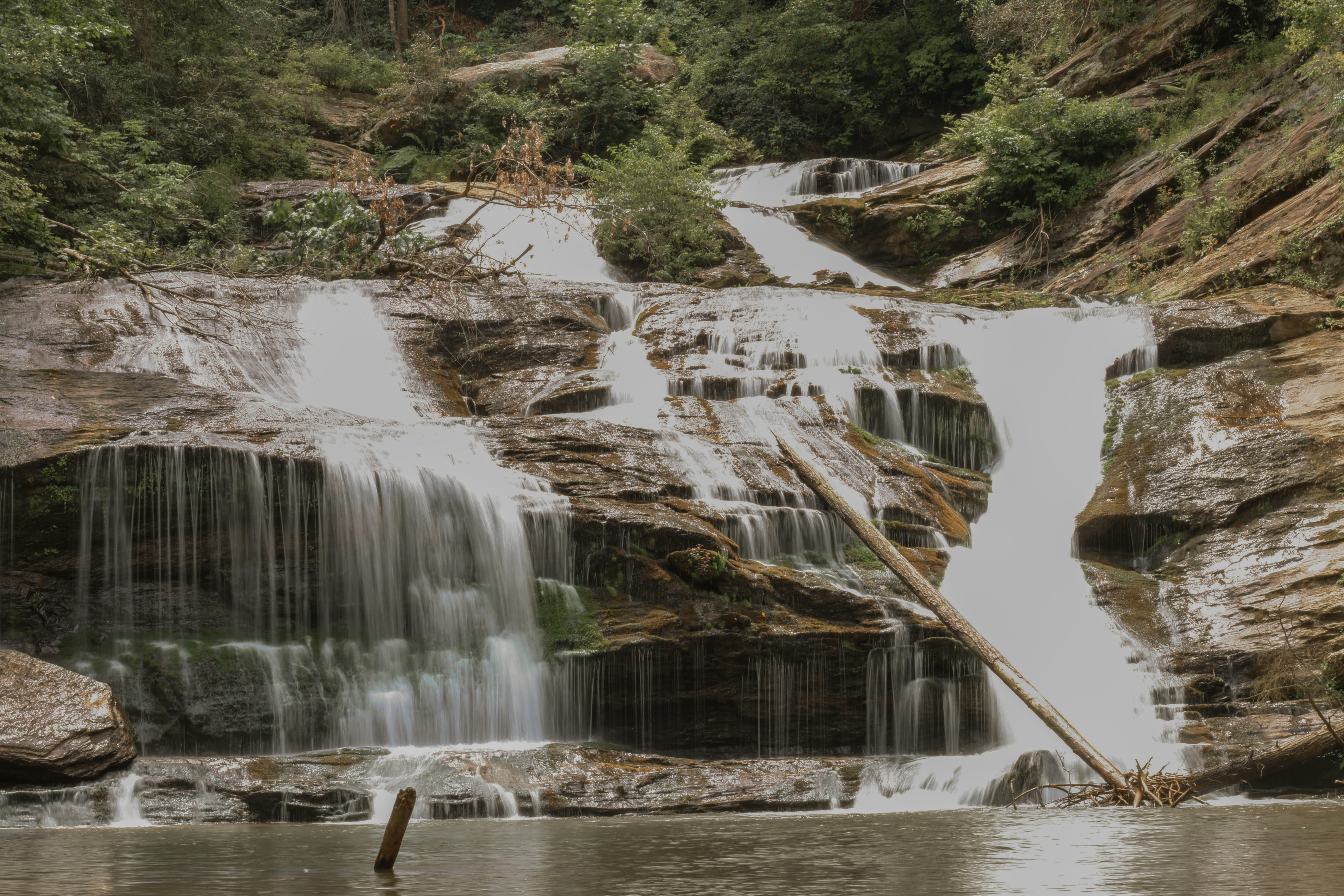 a man standing in a body of water near a waterfall
