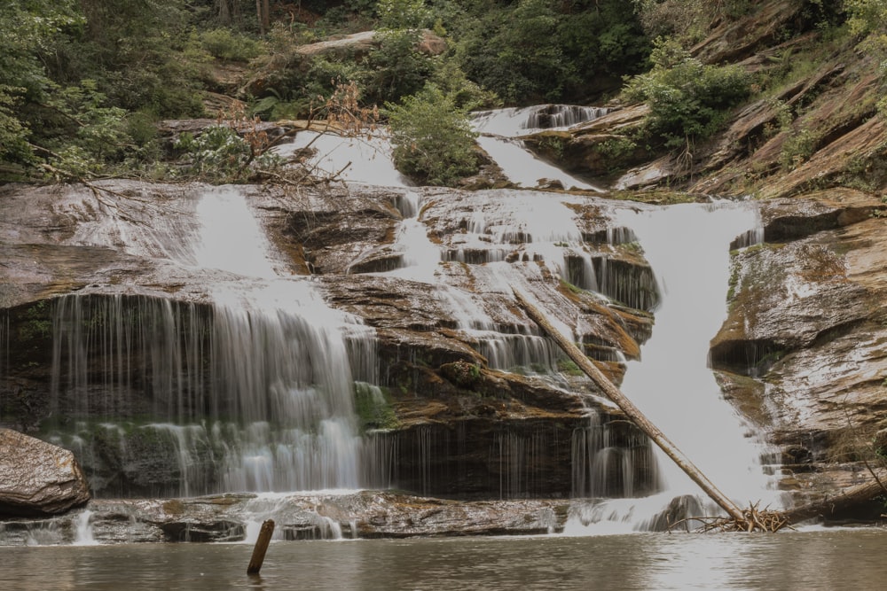 Un hombre parado en un cuerpo de agua cerca de una cascada