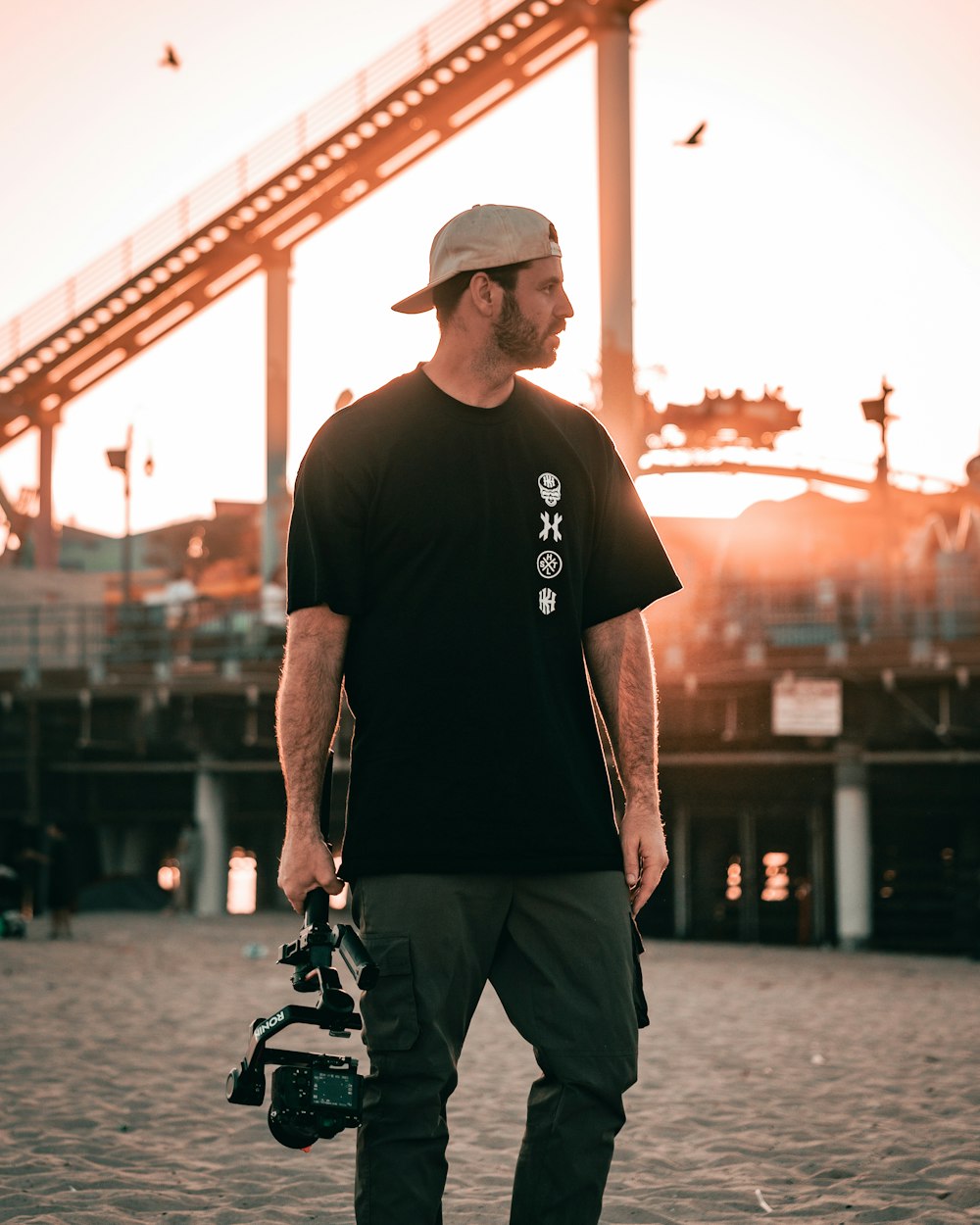 a man in a black shirt and hat holding a skateboard