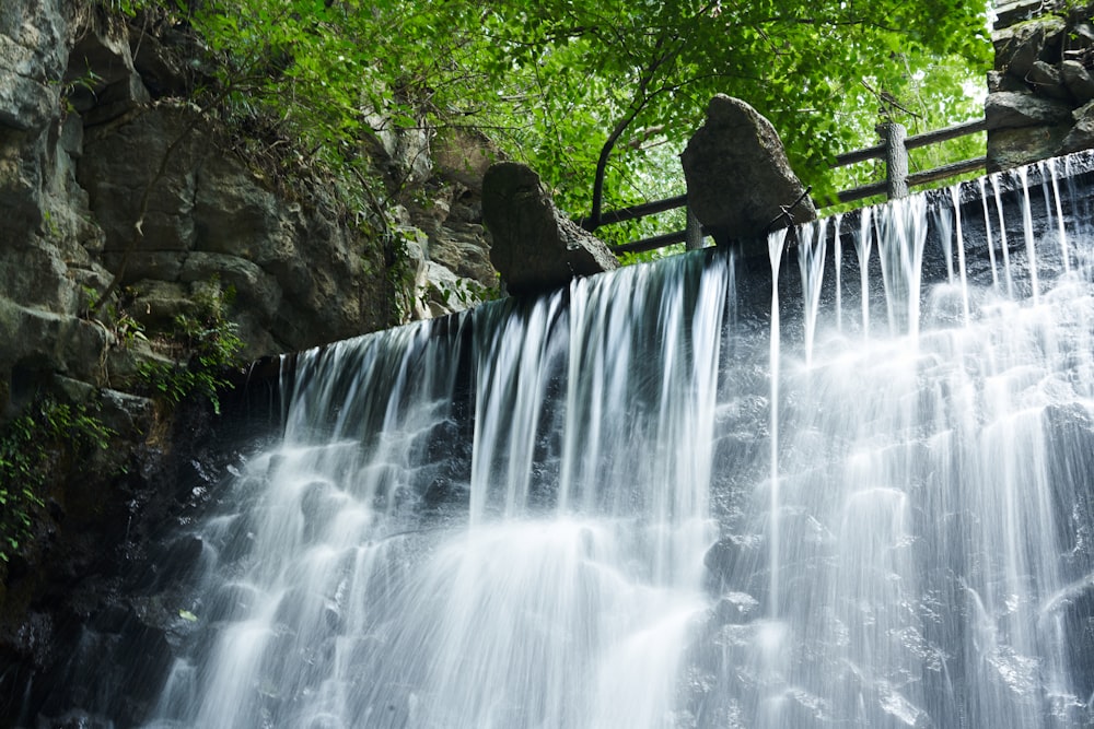 a waterfall with a wooden fence in the middle of it