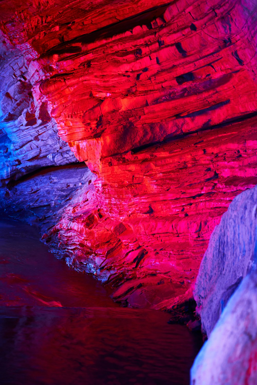 a red and blue cave with a river running through it