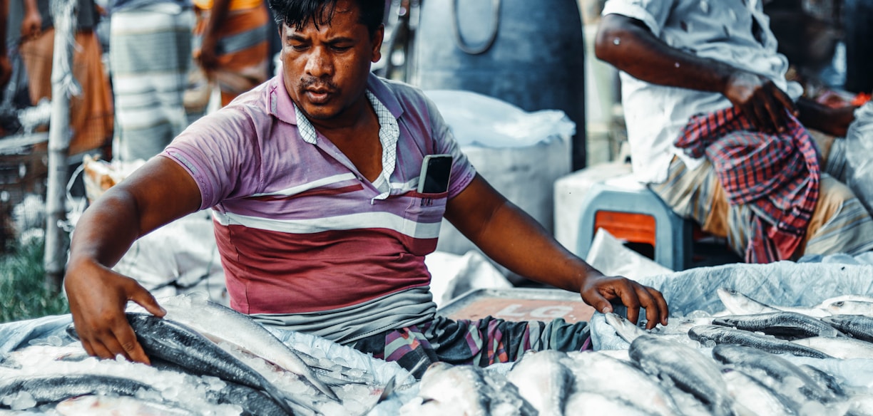 a man sitting in front of a pile of fish