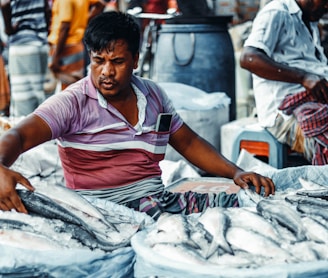 a man sitting in front of a pile of fish