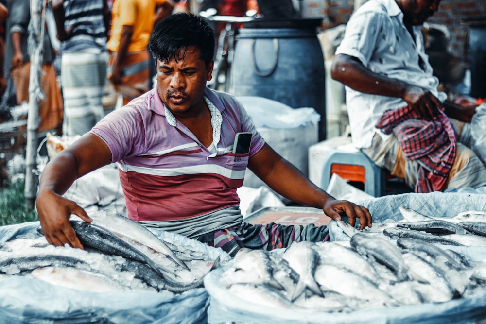 a man sitting in front of a pile of fish
