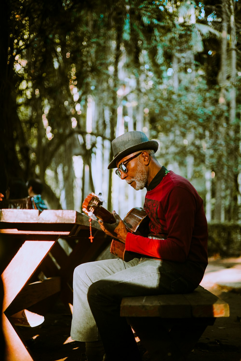 a man sitting on a bench playing a guitar