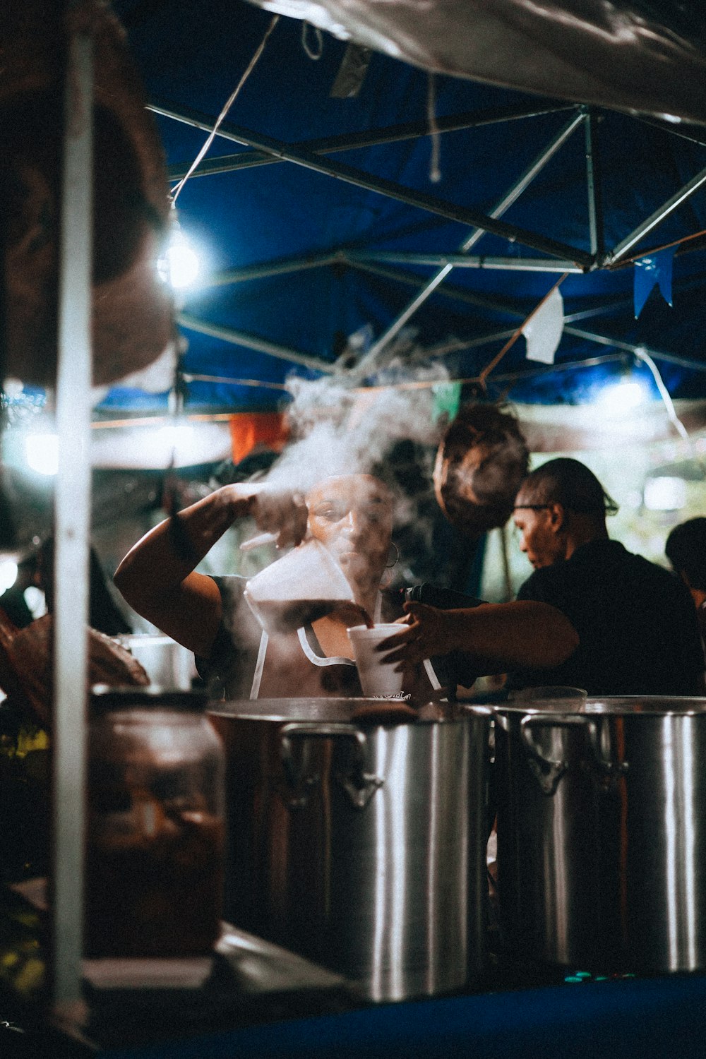 a group of people standing around a pot on top of a stove