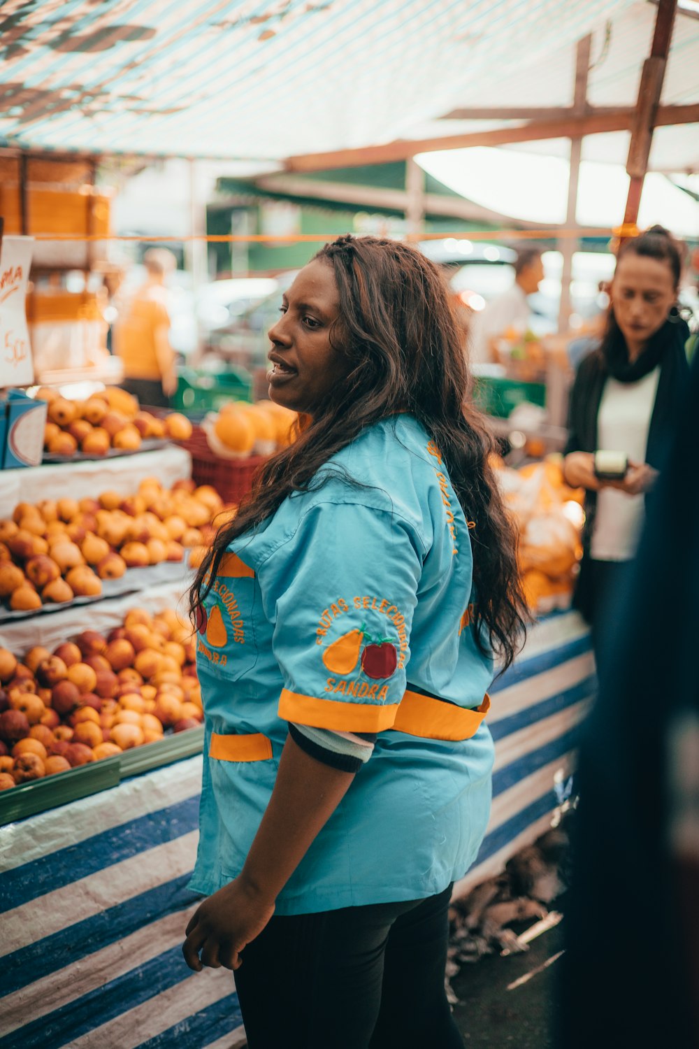 a woman standing in front of a fruit stand