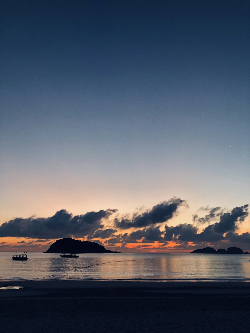 una vista del tramonto di una spiaggia con barche nell'acqua