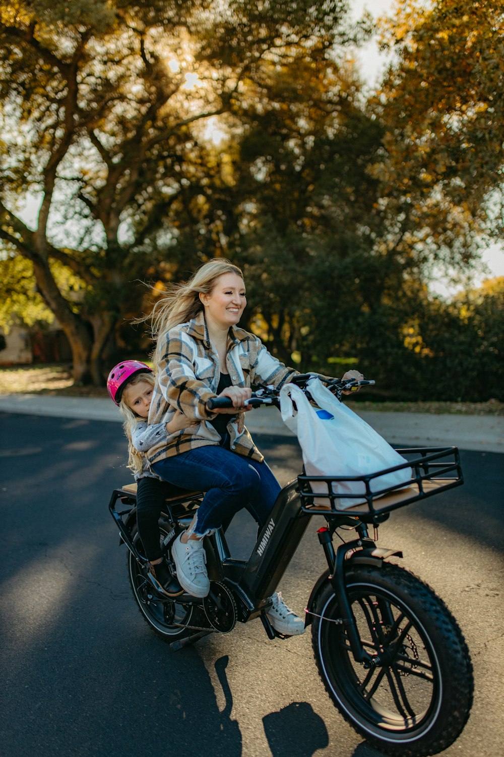a woman riding a bike with a child on the back