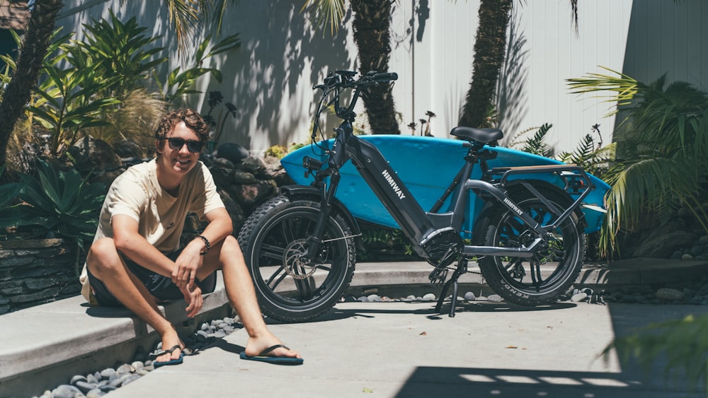 a man sitting next to a blue bike