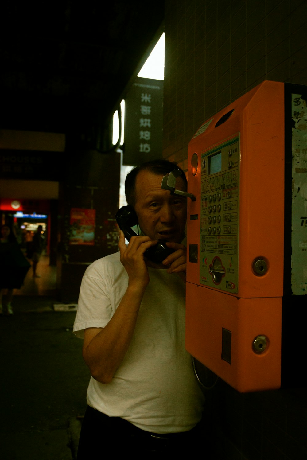 a man talking on a cell phone next to a vending machine