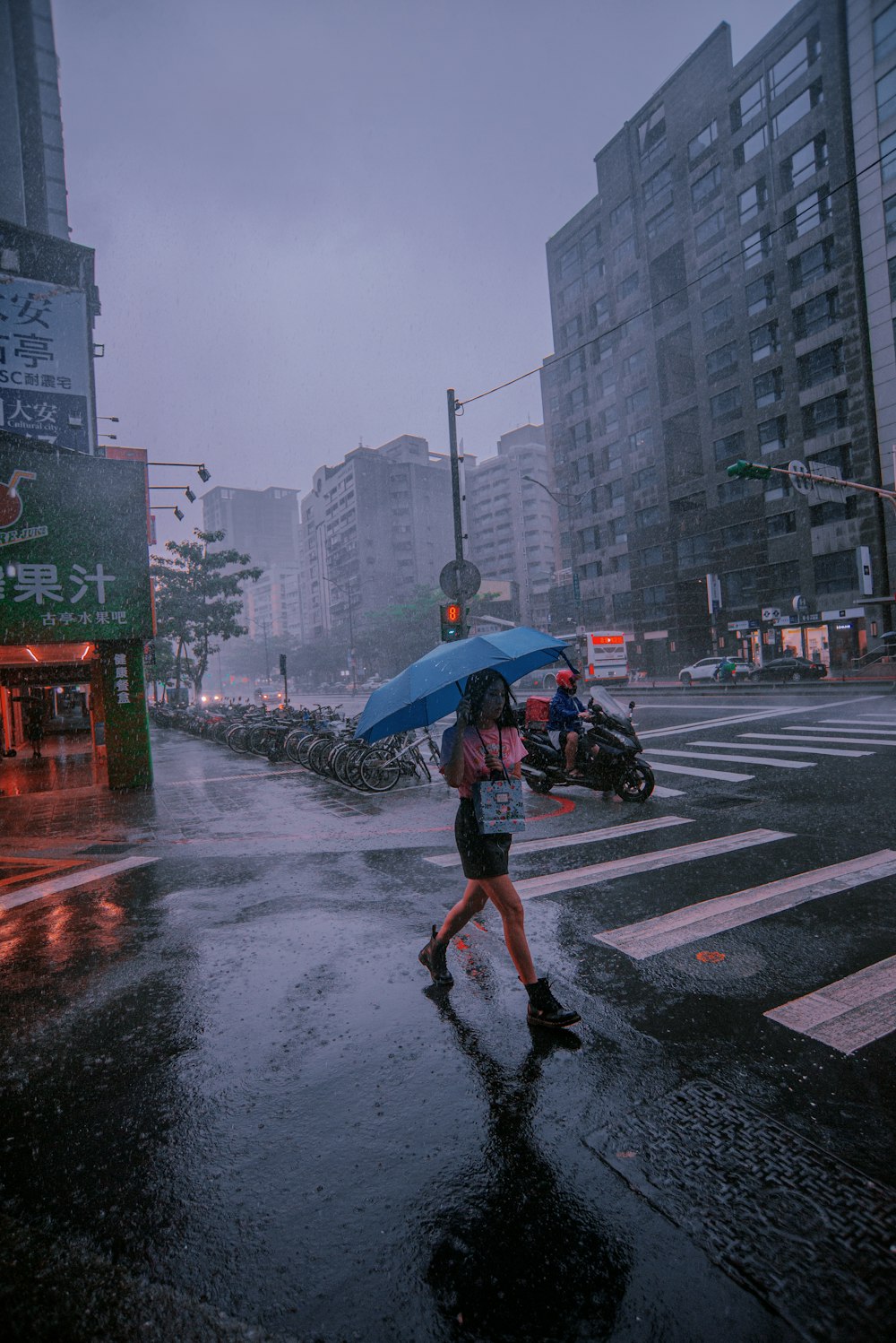 a woman walking across a street holding an umbrella
