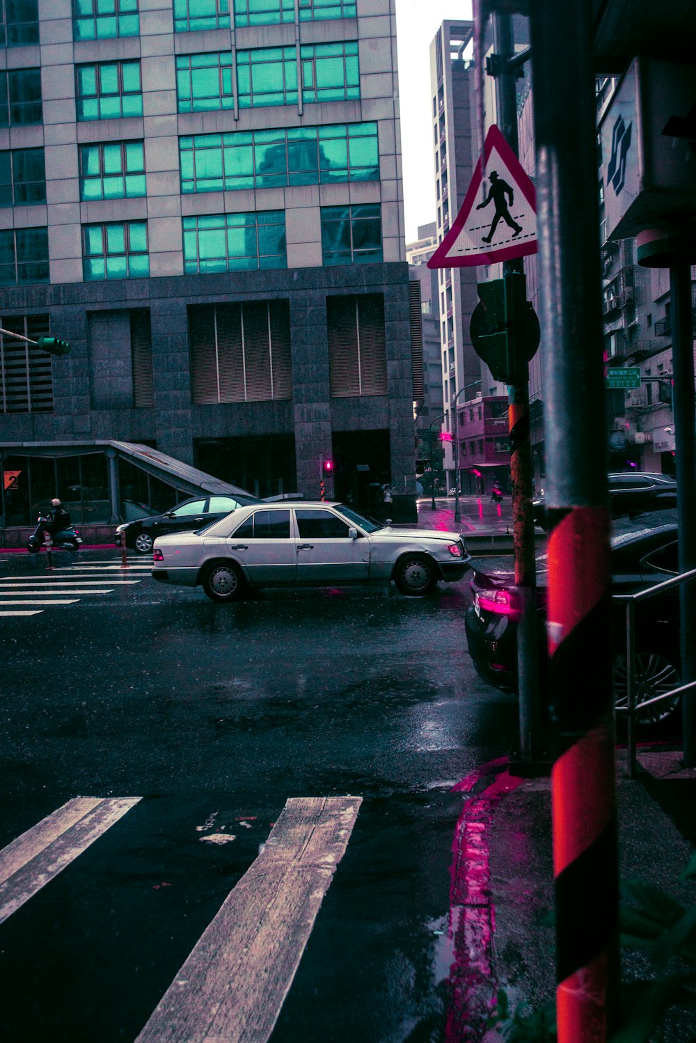 a white car driving down a street next to tall buildings