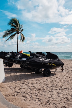 A group of jetskis lined up on the sandy shore of Browns Bay beach.