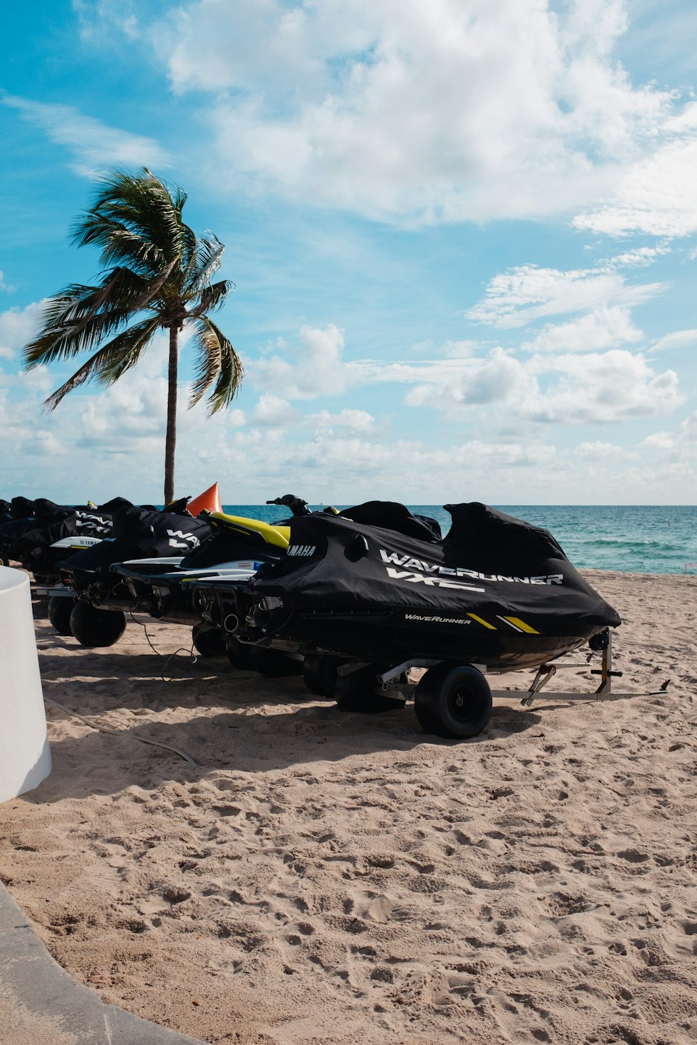 eine Reihe von Jetskis, die auf einem Sandstrand sitzen