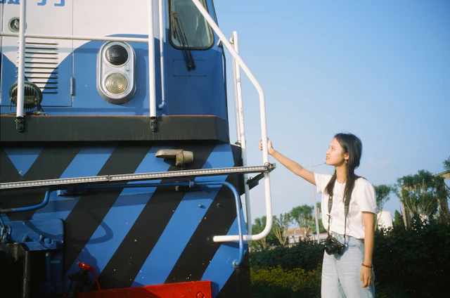 Portrait of Laurel Avery holding a vintage camera, with an old train station backdrop symbolizing the story’s historical journey.