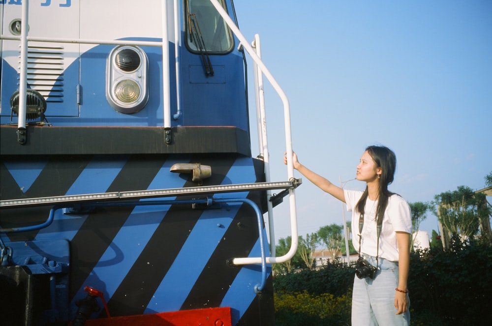 a woman standing next to a blue and white train