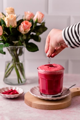 a person putting a spoon in a cup of red liquid