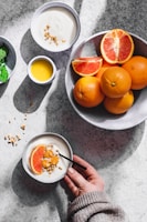 a person holding a bowl of oranges and yogurt