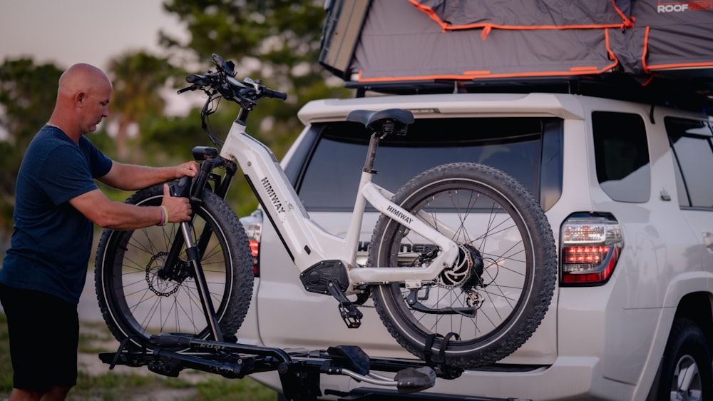 a man putting a bike on the back of a truck