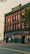 An older brick building with green accents is featured prominently. The words 'Hull Building' are visible at the top. The ground floor windows are boarded up, with a 'For Lease' sign in one window. On the sidewalk, a construction sign and traffic cone are present. A tree partially obscures the right side of the building.