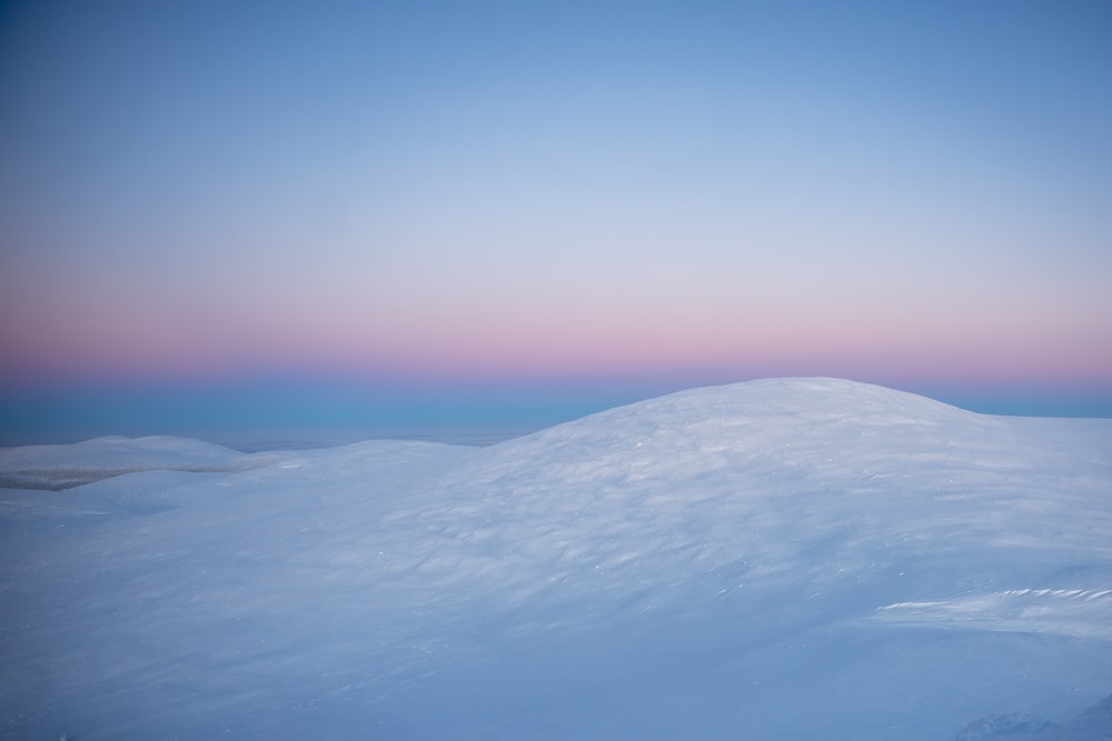 a snow covered hill with a pink sky in the background