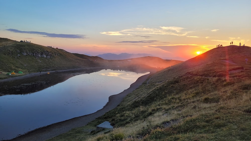 the sun is setting over a mountain lake