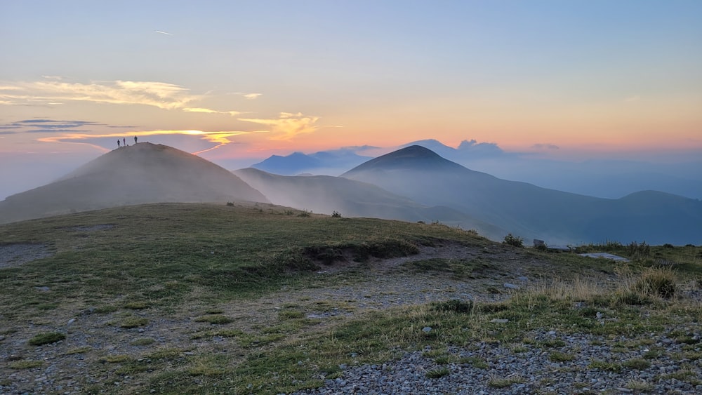 the sun is setting over the mountains on a foggy day