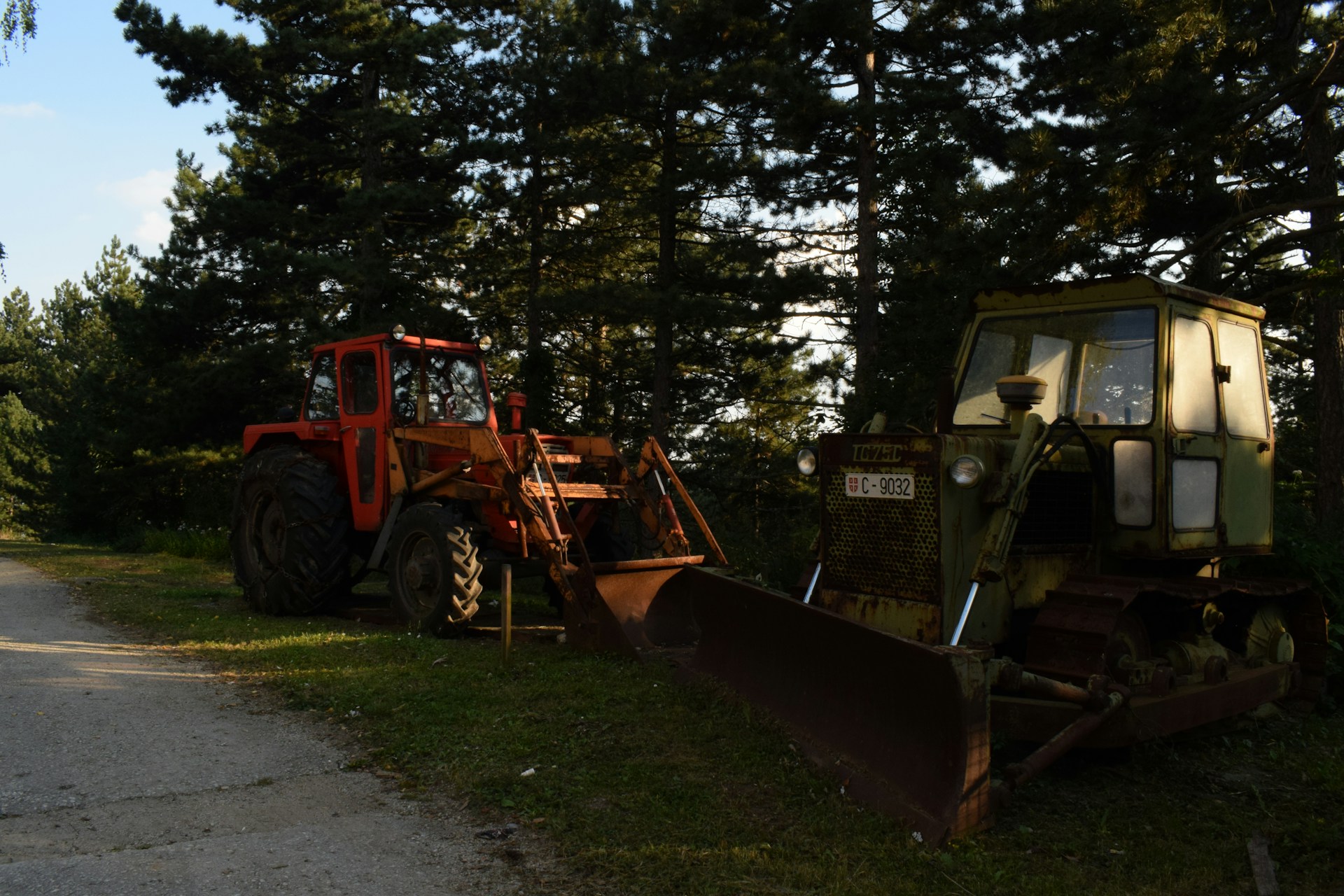 a tractor parked next to a plow on the side of a road