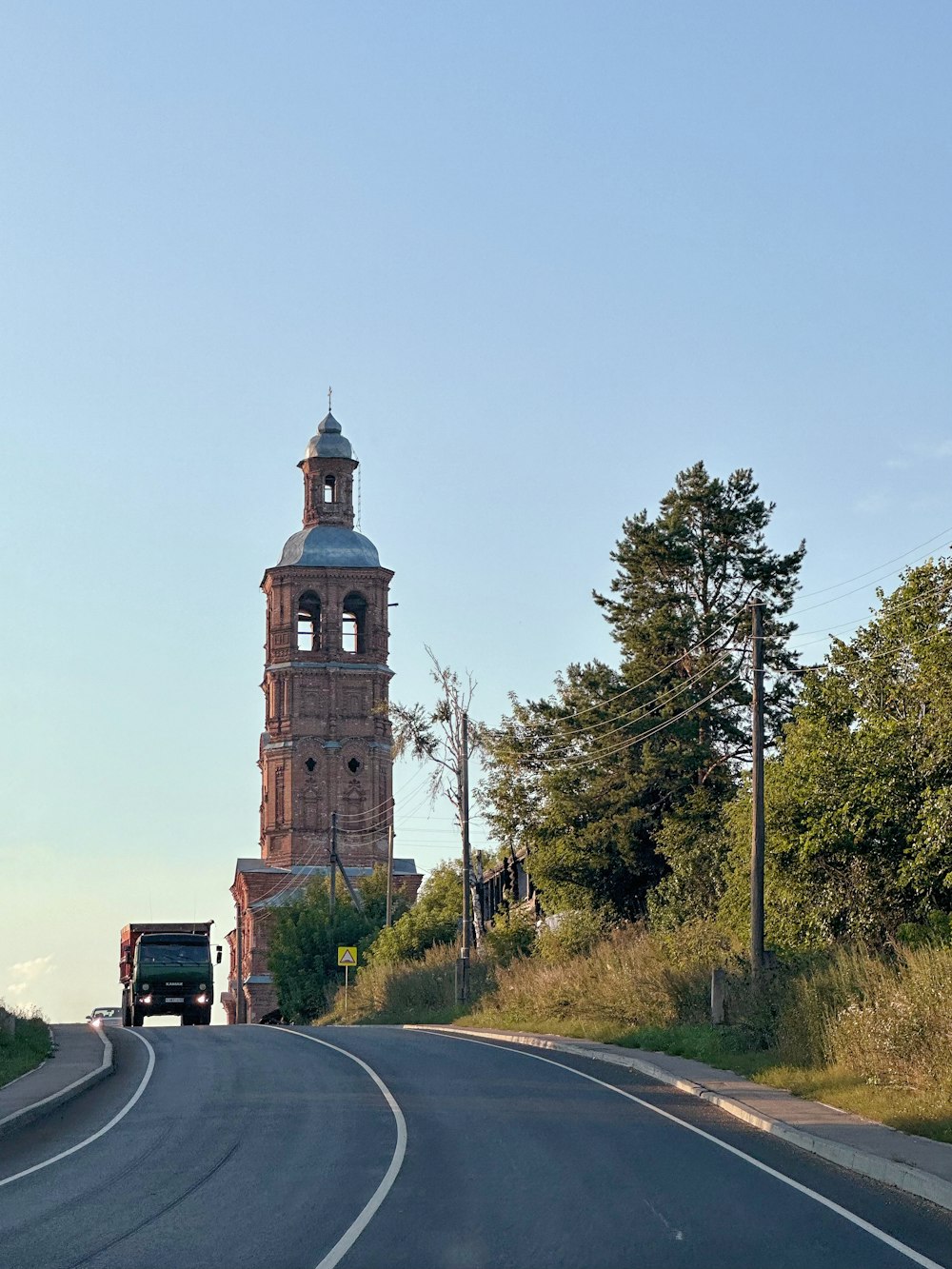 a truck driving down a road next to a tall tower