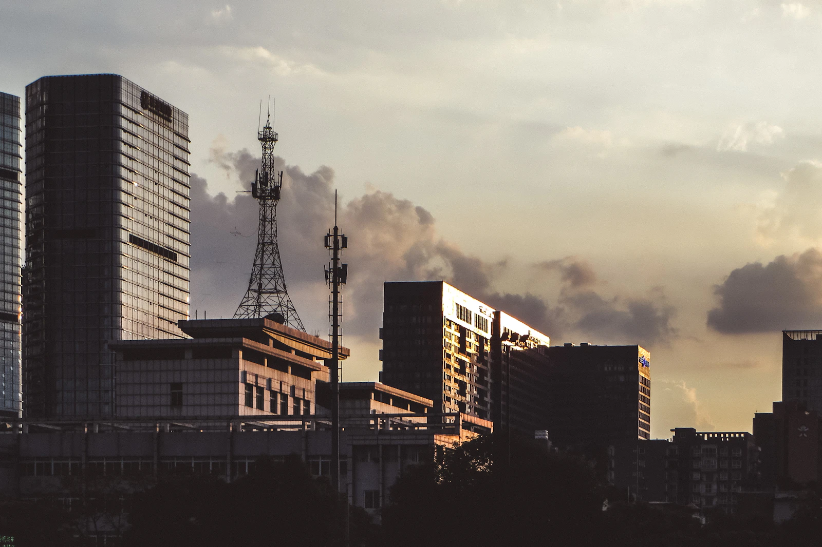 City skyline with tall buildings and a broadcast tower at dusk