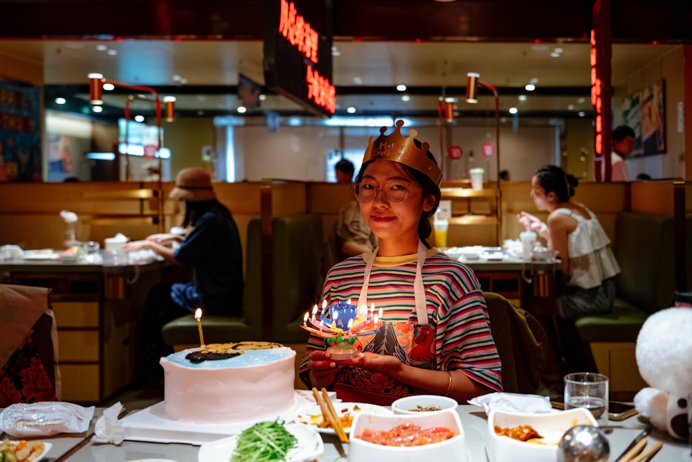 a woman sitting at a table with a birthday cake