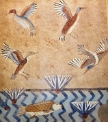 A mural illustrating birds in flight and fish swimming in a stylized aquatic scene. The background features a textured beige surface with small star-like patterns. The birds have vividly colored wings with shades of blue, brown, and white, while the fish are depicted below in a blue, zigzagged water pattern. There are also abstract geometric plant-like shapes present.