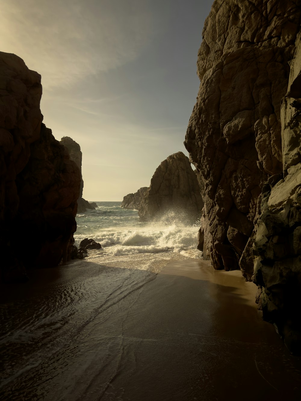 a sandy beach next to a rocky cliff